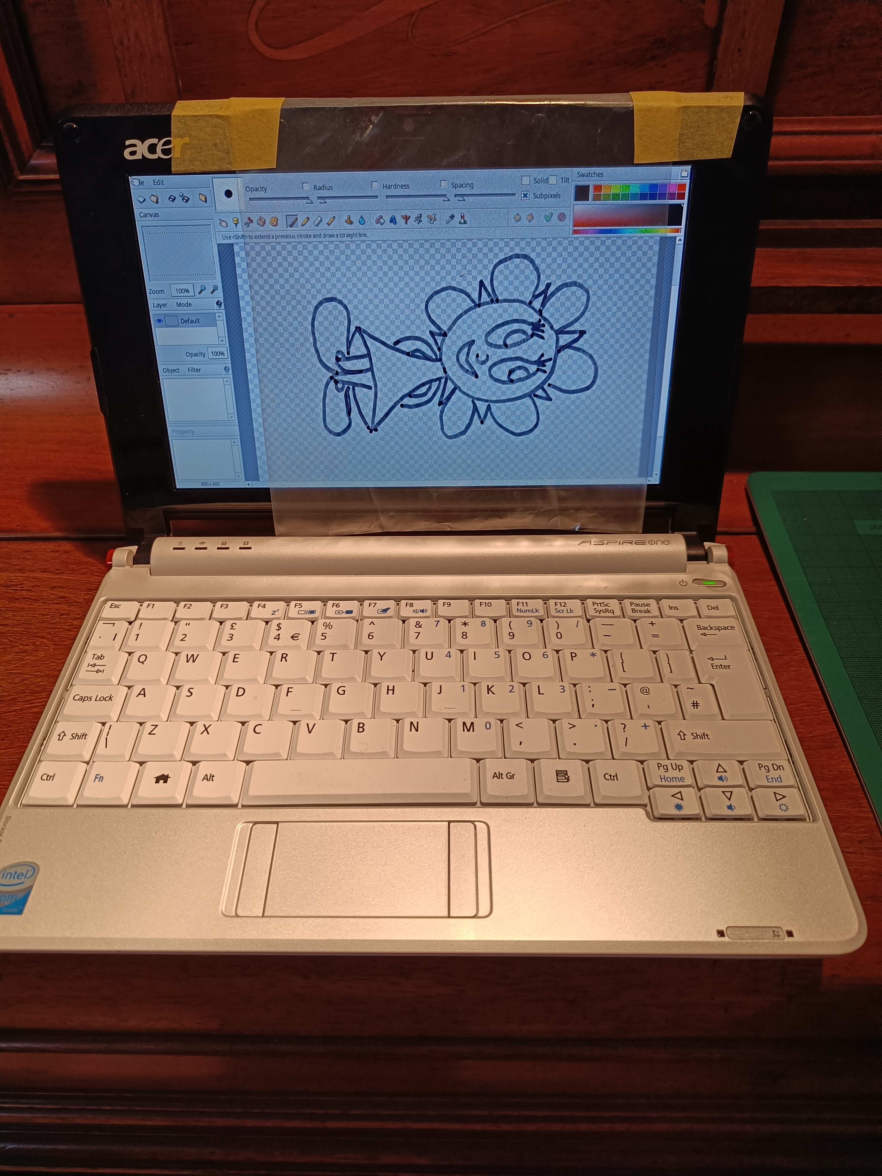 Piece of clear plastic taped to the screen of the small
netbook. On the plastic is a drawing of Sunny Funny done with a
sharpie. Sideways.
